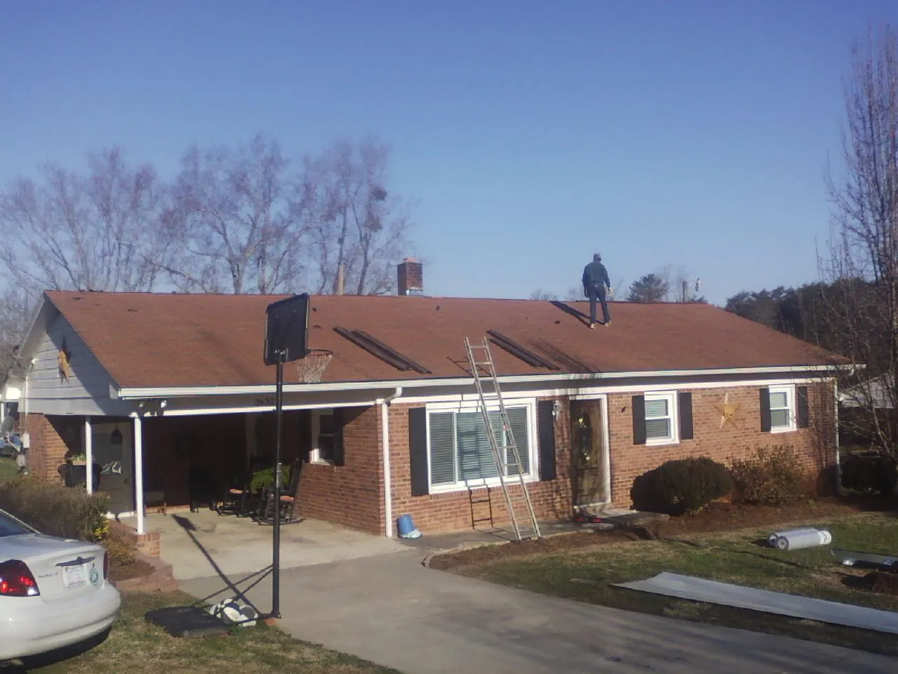 Roofer stripping a shingle roof on a brick ranch before metal panels in Vergas