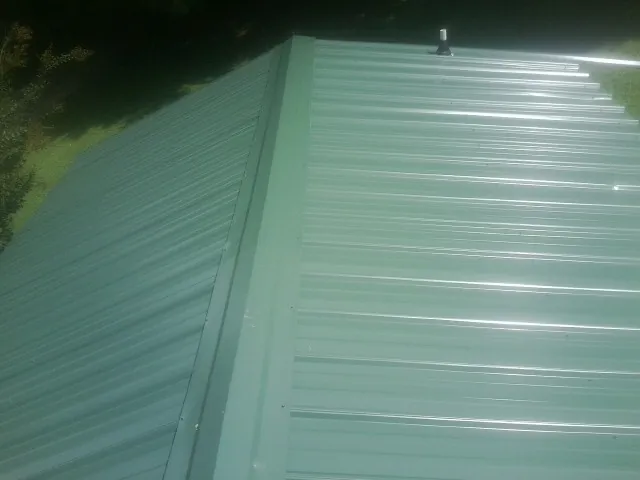 New green metal panels meeting at the ridge of a roof — Flat Roof Repair work by our crew in Vergas