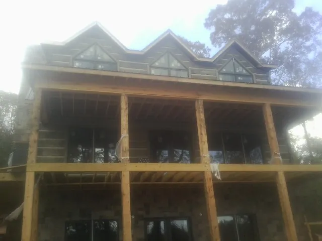 Dormers and porch framing on a large log home under construction — Roof Coating work by our crew in Vergas