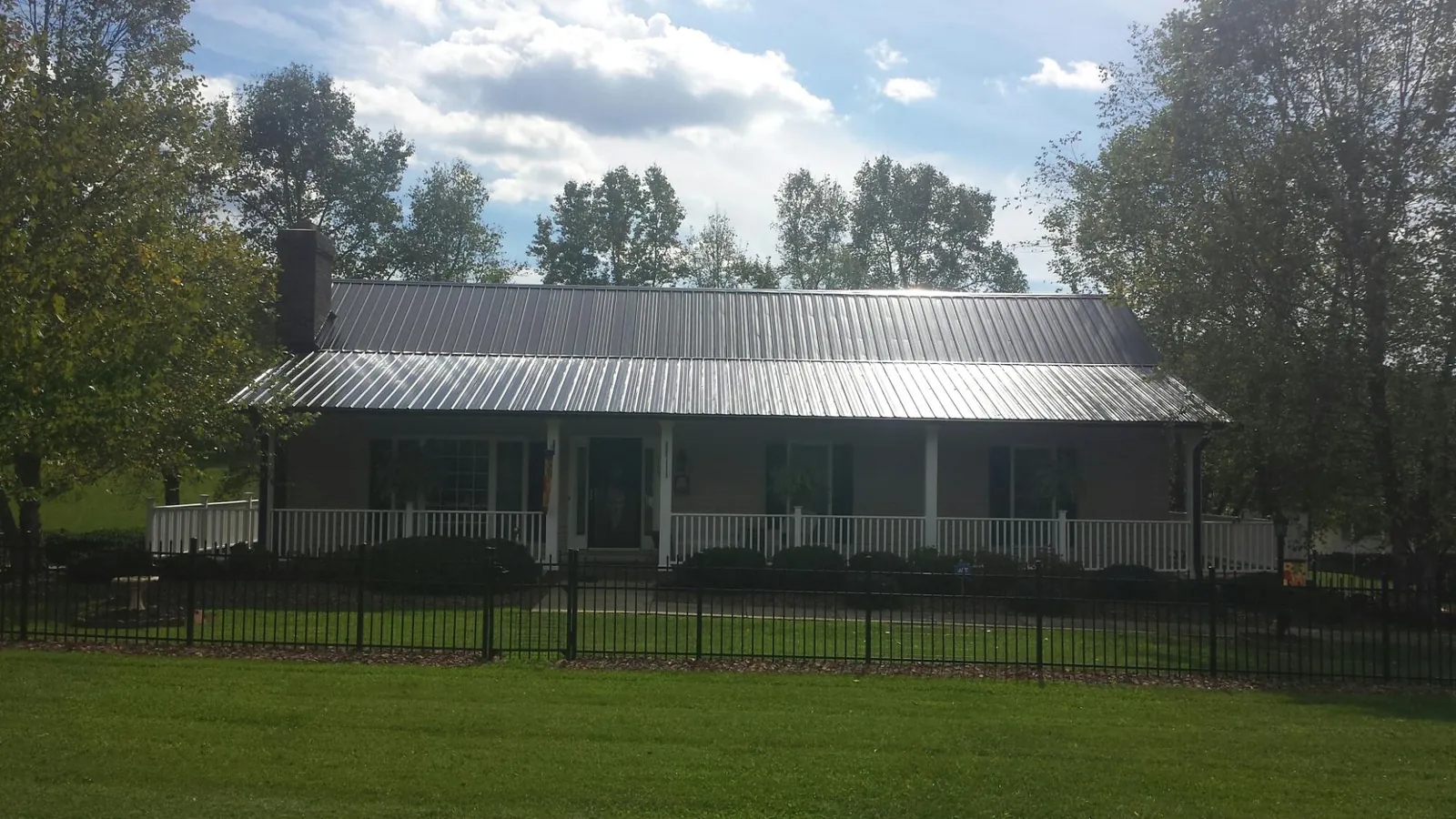 Gray metal roof on a brick ranch with a full width front porch — Gutter Guard Installation work by our crew in Vergas