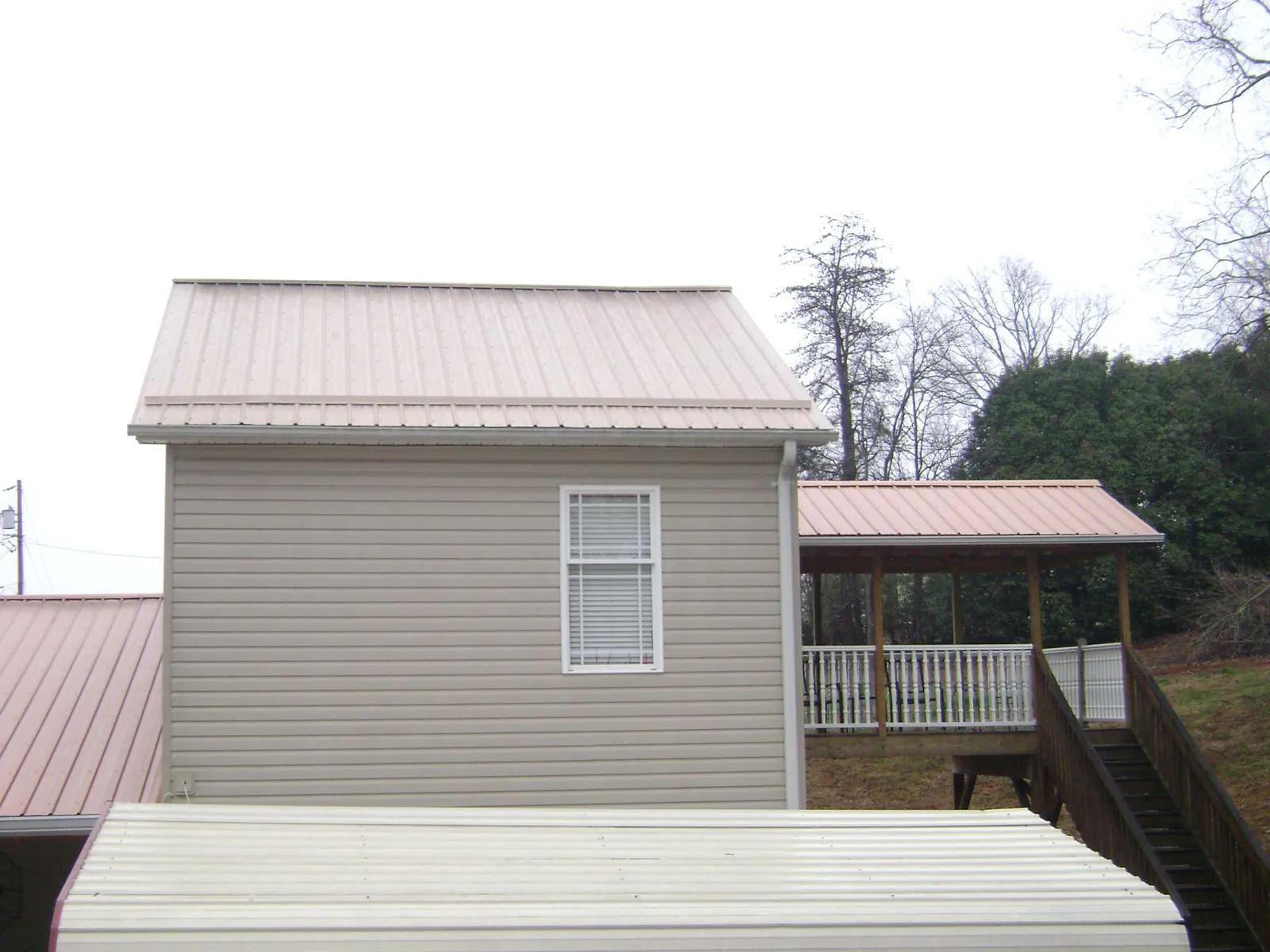 Tan metal roofs on a two story addition and attached porch, from a Roof Replacement job in Vergas