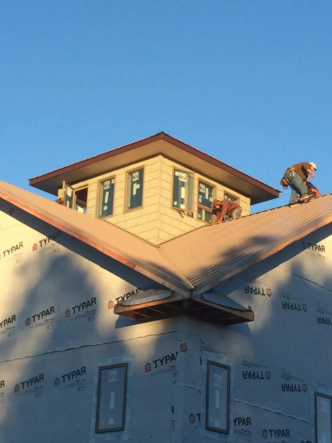 Roofers working around a rooftop cupola on a new metal roof at sunset — Roof Waterproofing in Vergas by Roofing Brothers